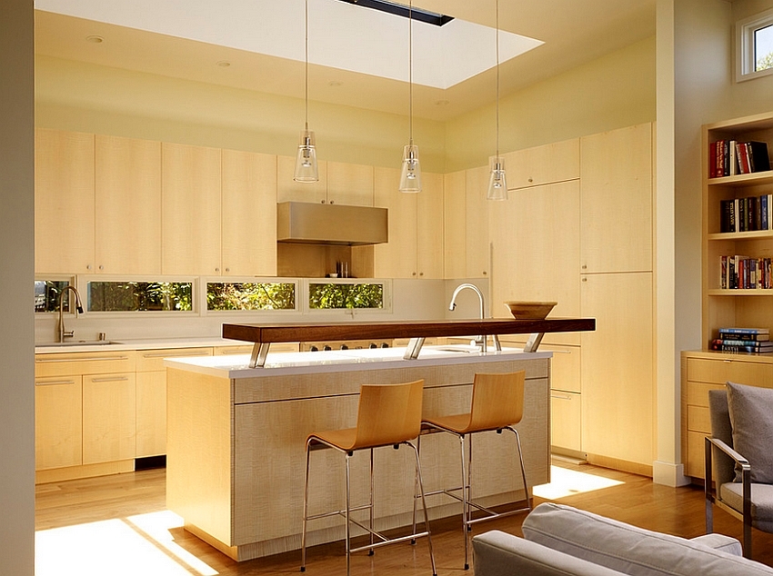 Световое окно в потолке кухни ярко освещает кухонный остров, а отраженный свет освещает и прилегающую гостиную.