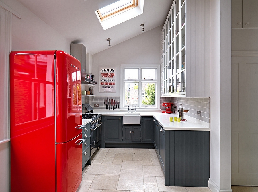 Великолепная кухня с серыми шкафами и красным акцентом в виде холодильника. Световое окно улучшает восприятие небольшого пространства.