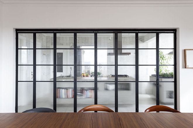 Перегородка из стекла и металла между кухней и столовой очень соответствует атмосфере квартиры.